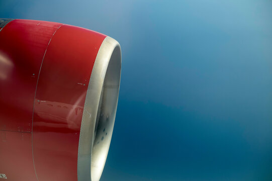 Close-up view of a red airplane engine cowling against a clear blue sky