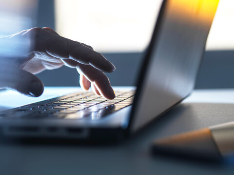 Man working online on his laptop computer with sunlight coming through window