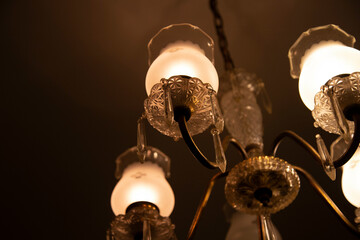 Elegant chandelier with illuminated frosted glass lamps against a dark backgroun, Auckland, New Zealand