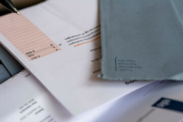 A close-up of a cluttered table covered with various documents, envelopes, and a pen, indicating administrative or financial tasks, Nijmegen, Netherlands