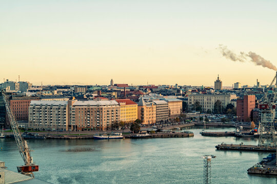 Aerial view of a city at dusk with buildings along the riverfront and an industrial area with smokestacks, Helsinki, Finland