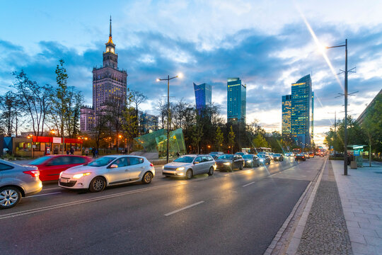 Twilight cityscape  of Warsaw with illuminated buildings and busy street traffic under a dusky sky, Poland