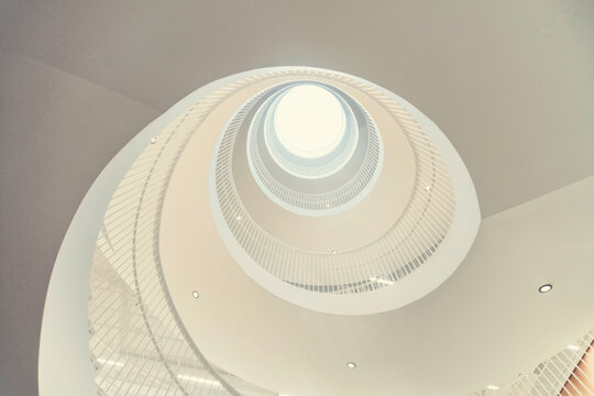 White spiral staircase leading up to a round skylight in a modern building, viewed from below, in the university library of Helsinki (Helsingin yliopiston p&auml;&auml;kirjasto Kaisa-talo)
