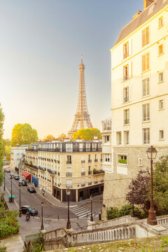 Parisian street view at dusk with the Eiffel Tower in the background and a clear blue sky, Paris, France