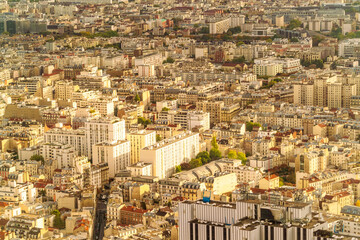 Aerial view of a dense European city of Paris with closely packed buildings and streets in soft sunlight, France