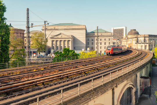 Red train moving on elevated tracks in Museums island with classic architecture  of Bode and pergamon museuem in the background during daylight, Berlin, Germany