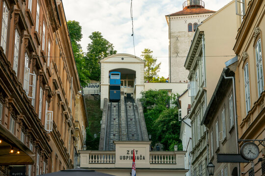Zagreb blue funicular railway ascends between historic buildings under a clear sky, Zagreb, Croatia
