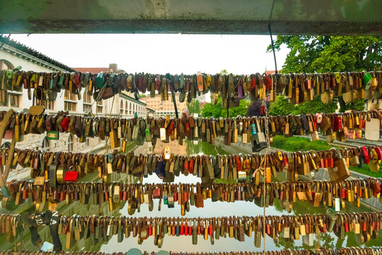 Rows of various antique locks and keys displayed on a sunny day with trees and buildings reflecting off the Ljubljana River, Ljubljana, Slovenia
