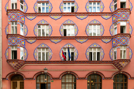 Facade of Vurnikova hi?a, a pink building landmark with intricate blue geometric patterns and arched windows, Ljubljana, Slovenia