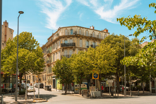 Sunny day view of Marseille city street corner with historic buildings and lush green trees, Marseille, France