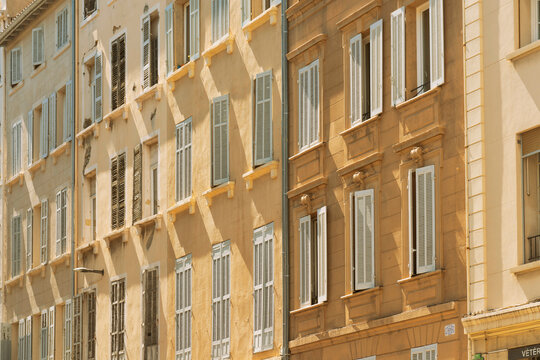 Sunlit facade of a beige building with multiple rows of windows and closed shuttersin the Provence, Marseille, France
