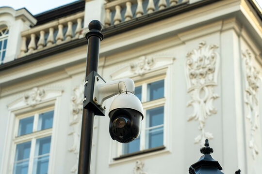 Security camera mounted on a pole in front of an elegant building with intricate architectural details, Krakow, Poland