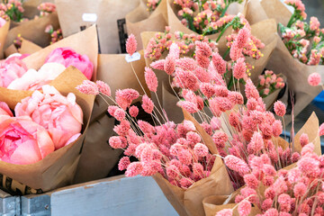 Fresh pink flowers and bouquets wrapped in brown paper on display at a flower market, Stockholm, Sweden.