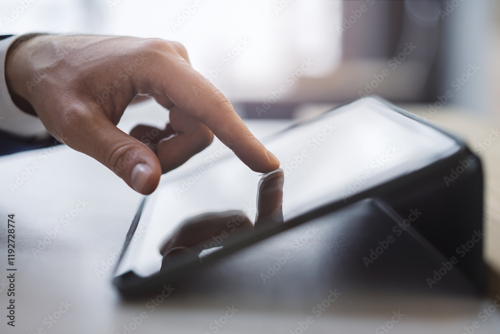 Poster close detail of a man's finger making contact with the screen of a sleek digital tablet resting on a