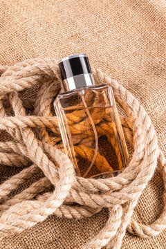 Elegant male perfume bottle with rope on burlap background