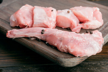 Fresh raw rabbit meat on wooden board with pepper seasoning