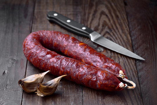 Spanish chorizo sausage and garlic on wooden table with knife