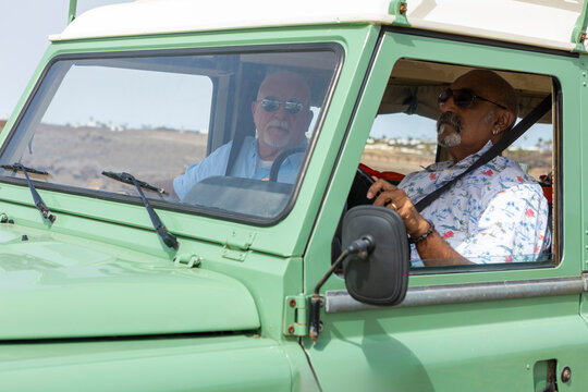 Gay senior couple in off-road vehicle on camping trip - Powered by Adobe