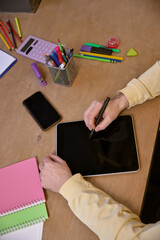 Focused image of person using stylus on tablet with surrounding stationery, symbolizing creativity...