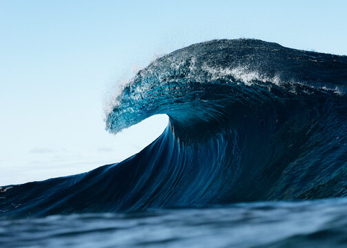 Majestic ocean wave cresting in the open sea at sunrise