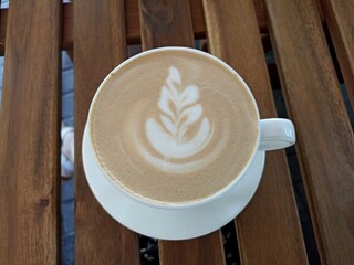 cup of coffee with a leaf design on the foam