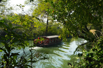 Fototapeta premium A ferry taxi glides through the serene waters of the national wetland park in Hangzhou City.