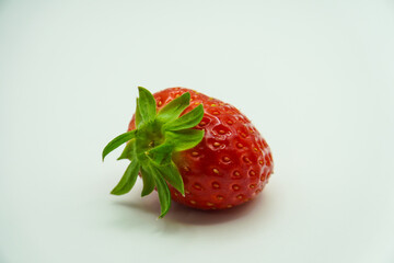 Freshly picked red strawberry with green leaves on a white background, close up shot