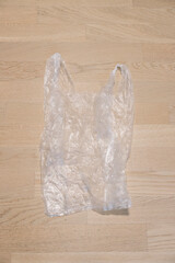 Crumpled transparent plastic bag lying on wooden floor promoting recycling, environment, and...