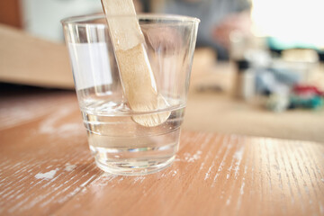 Clear plastic cup with stir stick on wooden surface in well lit room.