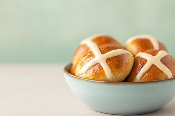 hot cross buns in light blue bowl on beige surface with minimal styling, easter baking