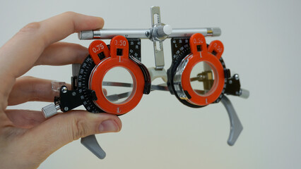 Optometry concept. Hand holding Trial frame with corrective lenses from lens set. Vision exam for glasses