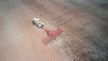 A single tractor with a trailed combination machine cultivates arable land before sowing crop...