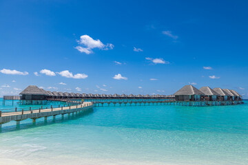 Beautiful sunny tourism destination tropical beach, Maldives. Jetty pathway into tranquil paradise island. Luxury water villas blue sea, perfect summer vacation landscape or holiday beachfront coast