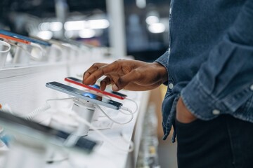 Close up view of man's hand that is touching and trying new smartphone in the store