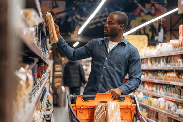 With shopping cart. Man customer is in the supermarket