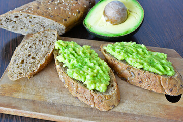 avocado toasts made of whole grain bread isolated on the cutting board   
