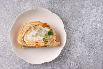 meringue roll with pear and mint on a white plate, copy space