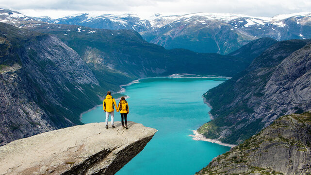 hikers couple enjoying view on the top of mountain near blue norway lake