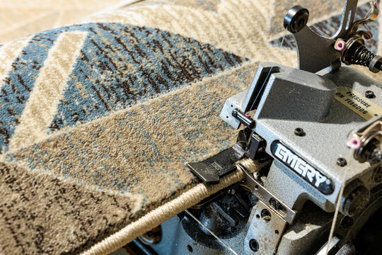 Industrial carpet overlocking machine stitching geometric pattern rug. January 9, 2024 Balti, Moldova