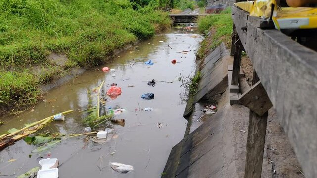 a small dirty polluted river carries away a lot of garbage in the rainy season