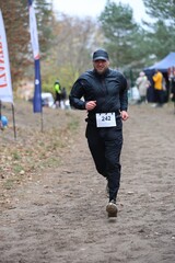 Gdynia, Poland - 11.17.2024: smiling mountain runner runs on a sandy road