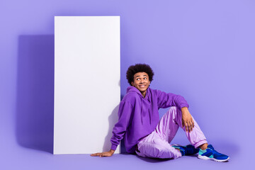 Full length photo of pleasant handsome guy purple clothes sit near smartphone display look empty...