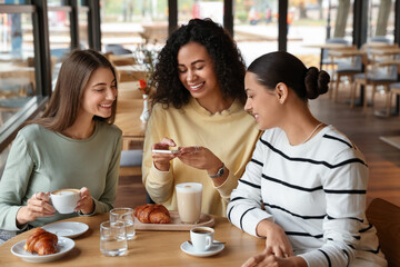 Woman taking picture of coffee drinks during meeting with her friends in cafe