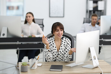 Saleswoman talking to client via headset at desk in office