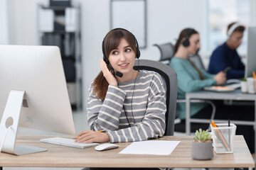 Saleswoman talking to client via headset at desk in office