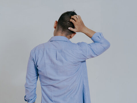 Rear view of Asian man scratching his head showing confused gesture, isolated on white background.
