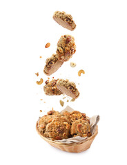 Yummy nut cookies falling into wicker basket on white background