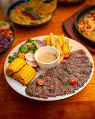 Medium rare tenderloin steak with musroom sauce. Served on white plate and grilled veggies and fries. Served on wooden table. Perfect for menu, catalogue, advertising or commercial use