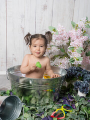 A little girl playing in a copper bathtub or bathing basin with a retro design, surrounded by rubber bath toys. A playful and cozy scene evoking childhood memories.
