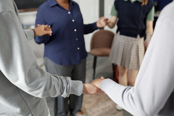 Close up of multiethnic group of teenagers standing in circle and holding hands during group...